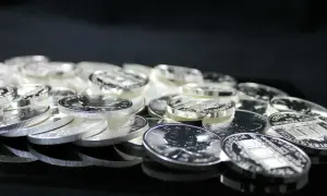 Stos monet ze srebra, błyszczące w świetle. Widać na nich detale, jak liść klonu i budynki. To inwestycja, która może być opodatkowana, czyli vat na srebro.