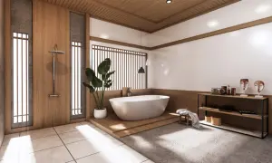 Minimalistyczna łazienka japandi z wolnostojącą wanną, drewnianymi elementami i kamiennymi detalami.