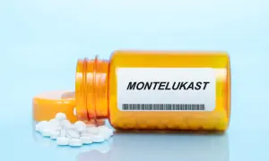 Pomarańczowa butelka z lekami na alergię, na etykiecie napis "MONTELUKAST". Kilka białych tabletek rozsypanych obok.