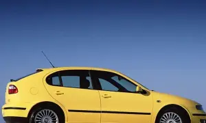 Żółty Seat Leon 2000, sportowy hatchback, zaparkowany na tle błękitnego nieba.