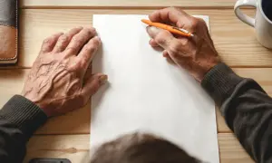 Ręce piszą testament. Zastanawiasz się, ile kosztuje testament notarialny?