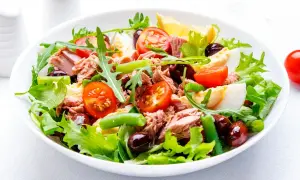 En fräsch sallad nicoise med tonfisk, ägg, tomater, oliver och gröna bönor på en bädd av sallad.