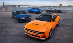 Pomarańczowy i niebieski Dodge Charger Hellcat obok szarego coupe, z mostem w tle.