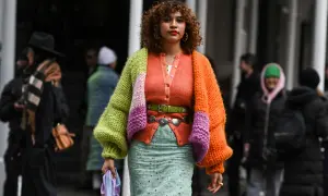 Bunte Strickjacke kombinieren: Ein Outfit mit Strickjacke in Orange, Grün und Lila, dazu ein gemusterter Rock und ein grüner Gürtel.