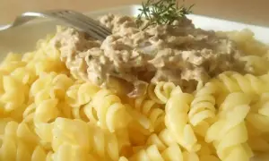 Pâtes fusilli généreusement garnies d'une sauce crémeuse aux pâtes au thon, décorées d'une branche de thym.