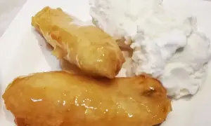 Två gyllene friterade bananer med honung serveras med en generös klick vaniljglass. En ljuvlig dessert!