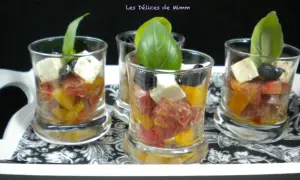 Quatre verrines apéro colorées avec tomates, olives, feta et basilic, présentées sur un plateau décoré.