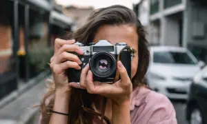 Dziewczyna z aparatem w rękach, idealna do kursu fotografii dla początkujących.