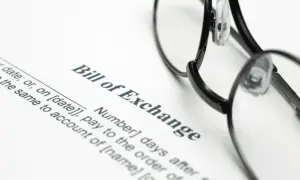 Okulary leżą na dokumencie "Bill of Exchange". To jest weksel, czyli papier wartościowy, który zobowiązuje do zapłaty określonej sumy pieniędzy.
