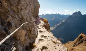 Klettersteig am Laufbacher Eck mit Seilsicherung und Blick auf schroffe Bergketten.