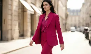 Kobieta w eleganckim garniturze w kolorze fuksjowym idzie ulicą.
