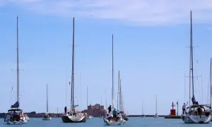 Veleggiate serene nella marina d'Angelo, con barche che solcano le acque azzurre sotto un cielo limpido.