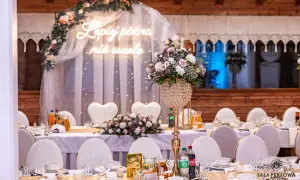 Eleganckie przyjęcie weselne na 20 osób. Stół udekorowany kwiatami, świecami i neonem "Lepiej późno niż wcale".