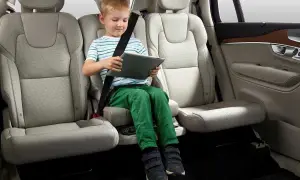 Niño en alzador coche, cumpliendo la normativa de seguridad vial. Viaja entretenido con su tablet.