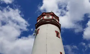 Wieża widokowa na Biskupiej Kopie z czerwonymi akcentami i antenami, na tle błękitnego nieba z chmurami.