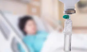 Pacjent w szpitalu otrzymuje kroplówkę. W tle widać łóżko szpitalne. Skutki uboczne nóż gamma mogą być poważne.