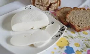 Świeży ser di bufala na talerzyku, obok kromki chleba.