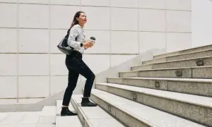 Frau steigt Treppen hoch, Kaffee in der Hand. Ein guter Weg, um abzunehmen durch gehen und fit zu bleiben.