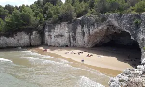 Spiaggia dei Colombi: una baia nascosta con una grotta marina, scogliere bianche e pini marittimi. Alcune persone si rilassano sulla sabbia dorata.