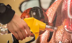Mano che inserisce la pompa gialla nel serbatoio con la scritta "DIESEL". Attenzione a non confondere la benzina nel diesel!