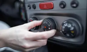 Dłoń kręci pokrętłem, regulując nawiew nagrzewnicy w samochodzie. Chłodne powietrze czy ciepło?