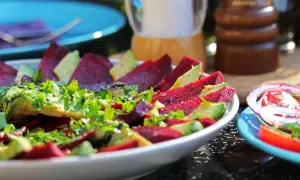 Pyszne carpaccio z buraka z awokado i świeżą natką pietruszki, doprawione pieprzem.