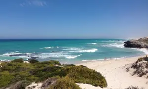 Türkisblaues Meer und Sanddünen im De Hoop Nature Reserve. Kleine Figuren genießen den Strand.
