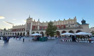 Sukiennice, jeden z najpiękniejszych zabytków w Krakowie, tętni życiem. Ludzie spacerują po Rynku Głównym, podziwiając architekturę i kupując kwiaty.