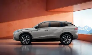 Elegancki SUV marki MG w kolorze piaskowym, zaparkowany w nowoczesnym wnętrzu z widokiem na góry.