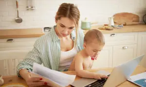 Mama pracuje przy laptopie, a dziecko próbuje jej pomóc. To codzienność, gdy macierzyński ile trwa.