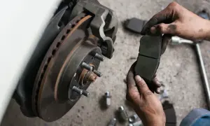 Mechanik trzyma nowe klocki hamulcowe, gotowe do wymiany przy zużytym hamulcu tarczowym.