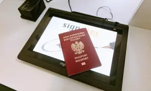 Polski paszport leży na ekranie urządzenia do podpisu elektronicznego, obok skanera linii papilarnych. Ważność paszportu jest kluczowa przy podróżach.