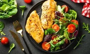 Deux blancs de poulet grillés avec une salade colorée, un repas sain parmi les 10 meilleurs aliments anti-cholestérol.
