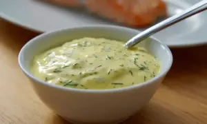 Krämig sås till lax, med dill och andra örter, serverad i en vit skål. En perfekt sås till din laxrätt.