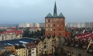 Widok na ceglaną wieżę kościoła i zabudowania miejskie Kołobrzegu.