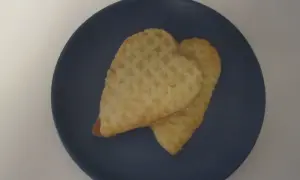 Två hjärtformade kex med socker på en mörkblå tallrik. Perfekta för parisare recept.