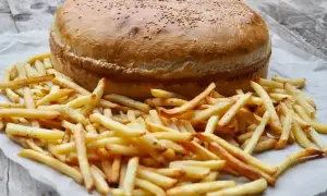 Ogromny burger z sezamem i złociste frytki, gotowe do podania. Ile piec burgery w piekarniku? Ten wygląda na gotowego!