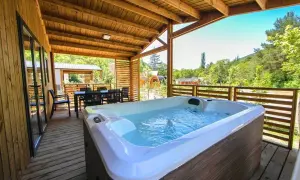 Terrasse en bois avec jacuzzi et table à manger, vue sur la nature. Idéal pour un séjour détente au camping de la ferme.