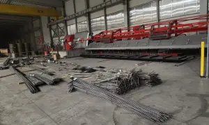 Stal zbrojeniowa w magazynie, gotowa do użycia w budowie. Maszyna do produkcji elementów zbrojeniowych w tle.