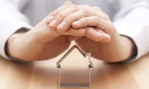 Mani che proteggono una casetta, simbolo di un comproprietario non vuole vendere.