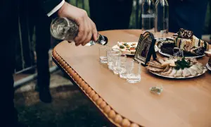 Na weselu nalewana jest wódka do kieliszków. Obok stoją zakąski i tort. Ile wódki na wesele?