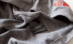 Szara koszulka z metką: 92% poliester, 8% spandex. Poliester co to za materiał? Wytrzymały i szybkoschnący, idealny do odzieży sportowej.