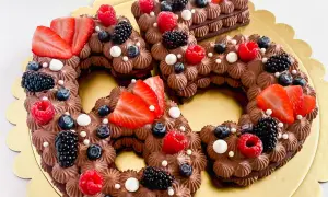 Una torta numero cioccolato, decorata con fragole, lamponi, mirtilli e more.