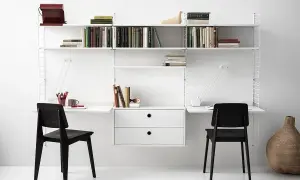 En stilren stringhylla montering med två arbetsplatser, böcker och dekorationer.