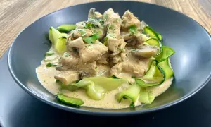 Pyszny keto obiad: kurczak w sosie śmietanowo-grzybowym z cukinią w kształcie wstążek, posypany natką pietruszki.