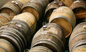 Botti di legno impilate, alcune con bicchieri di birra in attesa di essere degustate.