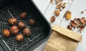 Châtaignes grillées dans un air fryer, prêtes à être dégustées. Les peaux éparpillées témoignent de leur préparation facile.