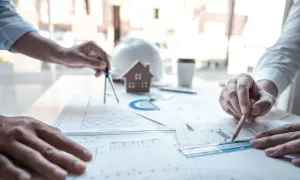 Architetti al lavoro su progetti edilizi, tra cui quelli che rientrano nella CILA. Si vedono mani che usano compasso, matita e righello sui disegni.