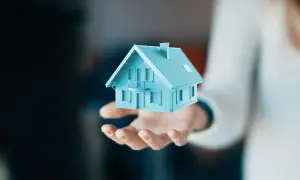 Dłoń trzyma błękitny model domu. Czy to darowizna? Co to znaczy?