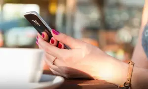 Kobieta z pomalowanymi paznokciami trzyma telefon, szukając informacji, jak zmienić dźwięk powiadomień w Messengerze.